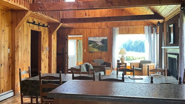A spacious wooden interior with a central island, seating area, and a fireplace. - Lakefront-Family & Pet Friendly-Adirondack Cabin (Indian Lake)