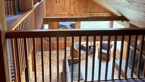 A wooden interior with a sloped ceiling, a balcony with a railing, and a ceiling fan. - Lakefront-Family & Pet Friendly-Adirondack Cabin (Indian Lake)