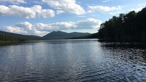 Un lago tranquilo con montañas al fondo y un cielo despejado.