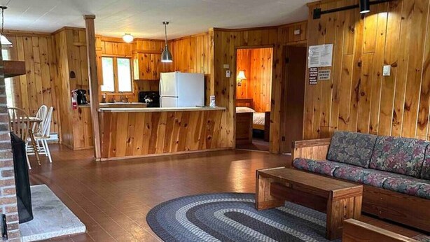 Un interior de madera con una cocina, un sofá y un tapete estampado.