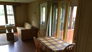 Ein Essbereich mit Tisch und Stühlen, einer Couch und einem Fenster mit Vorhängen.