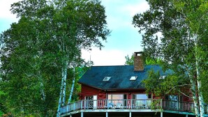 Eine zweistöckige Holzhütte mit Balkon, umgeben von Bäumen.