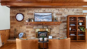 A cozy living room with a fireplace, a clock, and a bookshelf.