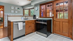 A kitchen with wooden cabinets, a built-in oven, a sink, and a window with a view of trees.