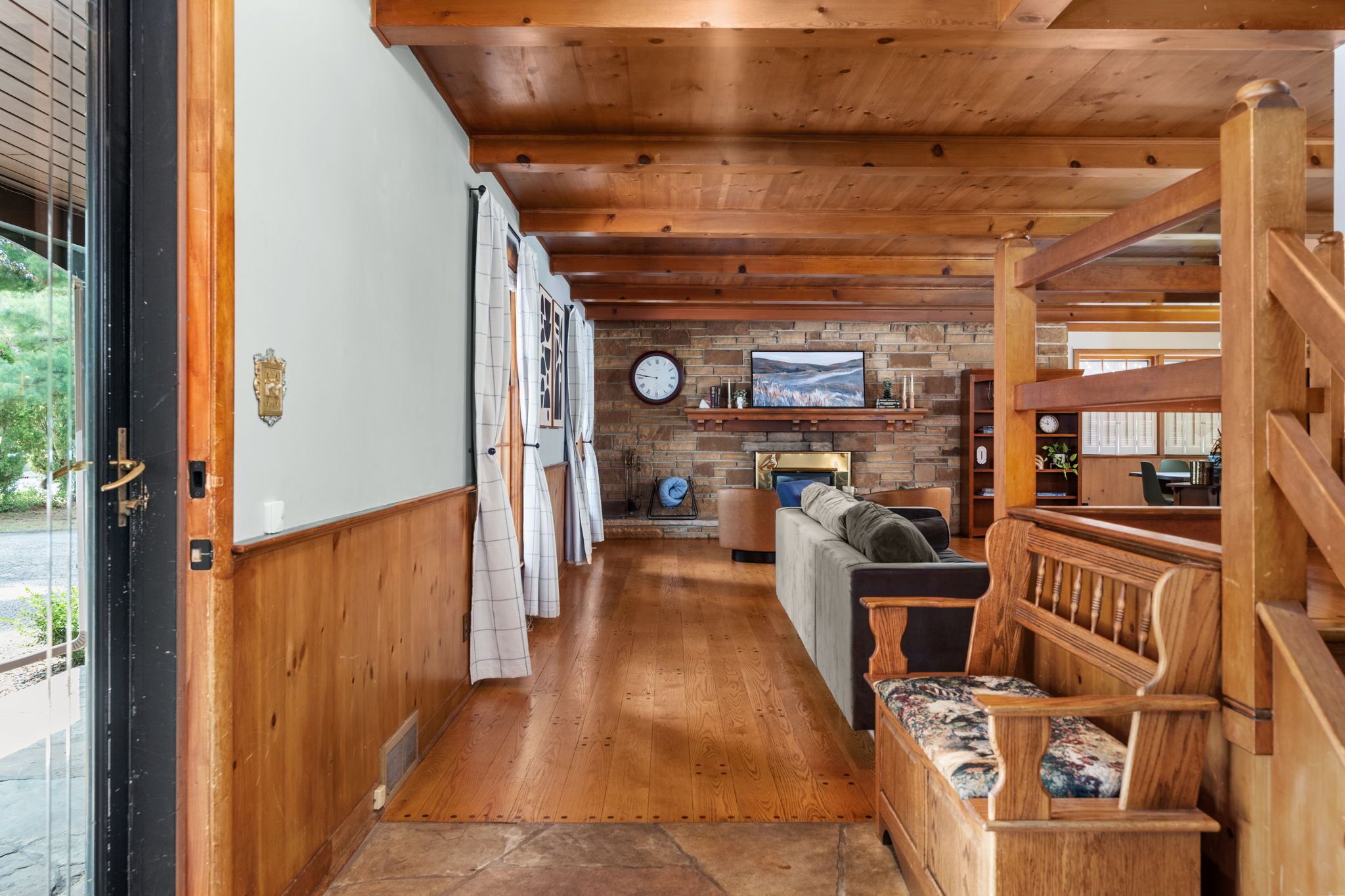 A wooden interior with a fireplace, a sofa, and a wooden bench.