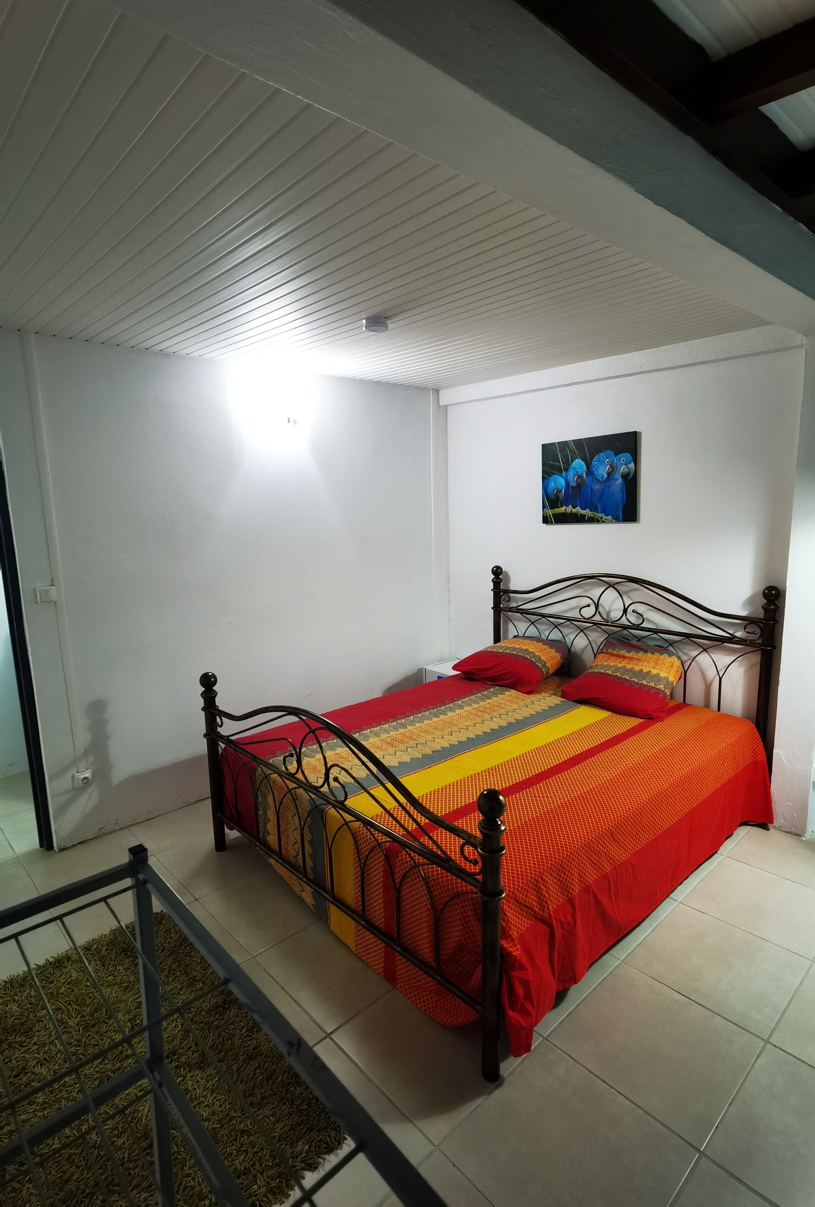 A bedroom with a bed, a ceiling fan, and a wall-mounted picture.