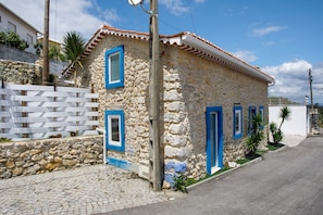 A stone building with blue-framed windows and doors, a cobblestone path, and a white fence. - Holiday Home 'Castelos Azul' with Private Garden, Wi-Fi and Air Conditioning (Ourém)