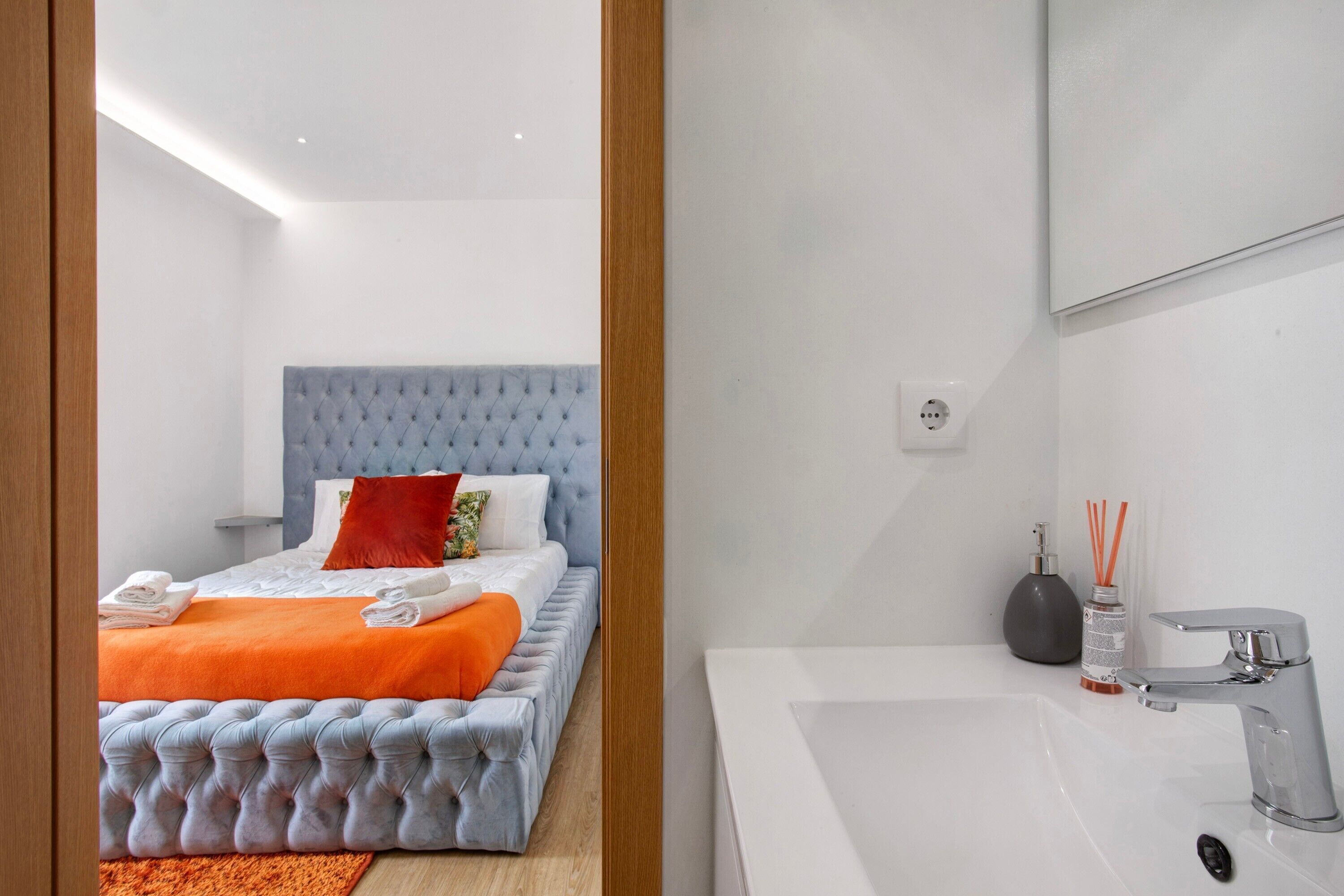 Ett modernt hotellrum med en stor säng, ett badrum med badkar och en spegel.