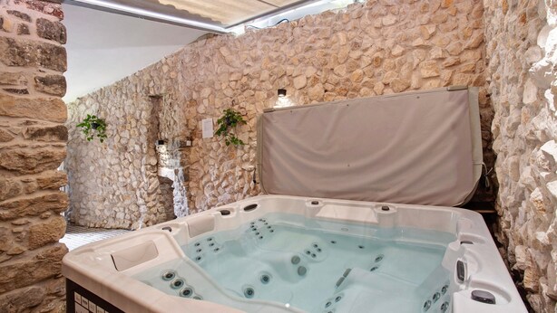 Una habitación con paredes de piedra y una bañera de hidromasaje.