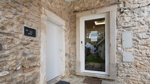 Fachada de un edificio de piedra con puerta, ventana y un cartel.