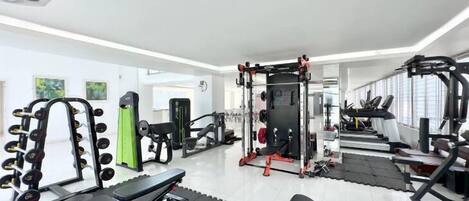 A gym with various exercise equipment, including dumbbells, a bench, and weight machines.