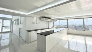 A modern kitchen with a central island, large windows, and a city view. - 250 sqft 2 Studio Apt Pool and Sauna (Dhaka)