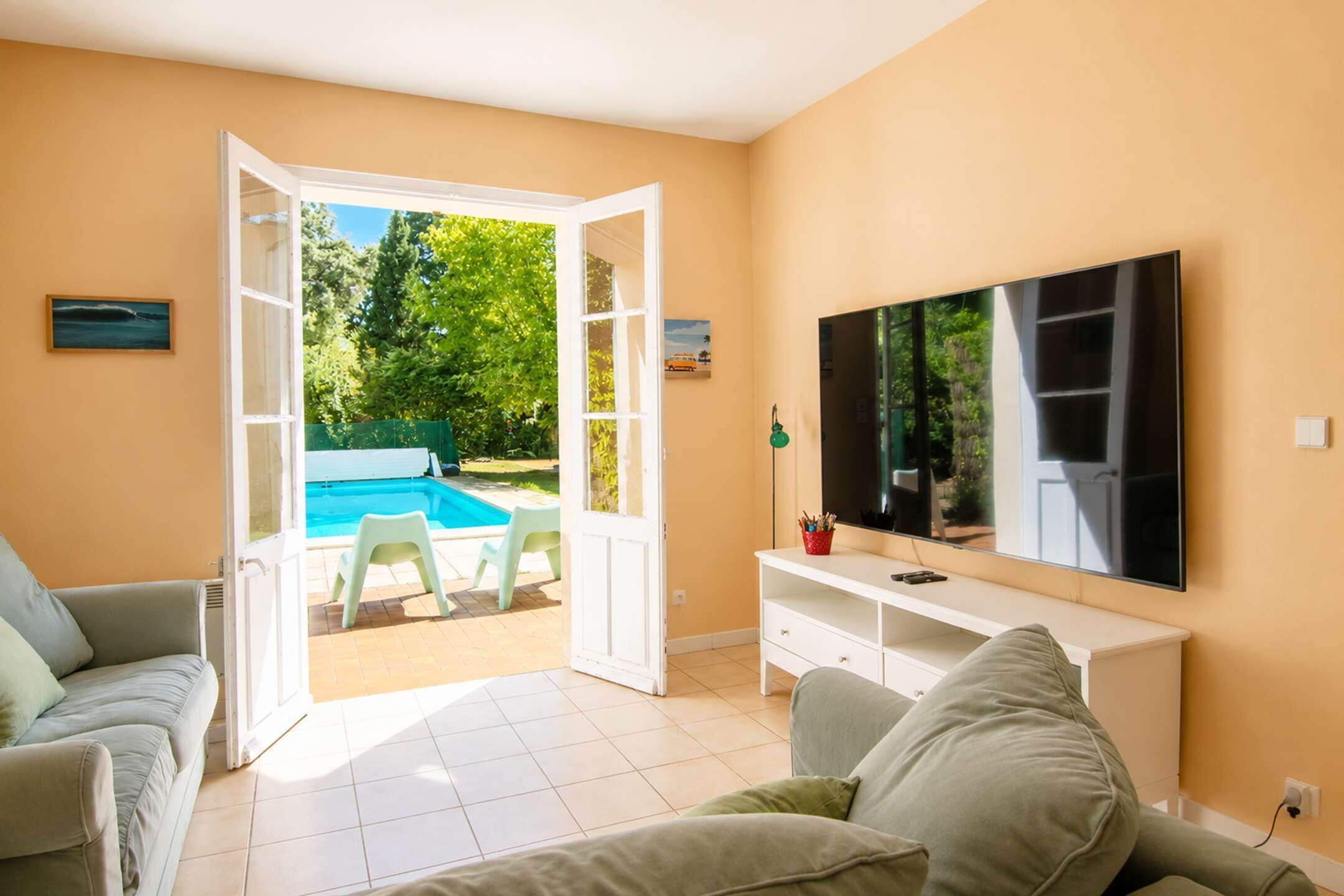 Ein Wohnzimmer mit Fernseher, einer Couch, einem Couchtisch, einem Pool und einer Tür, die nach draußen führt.