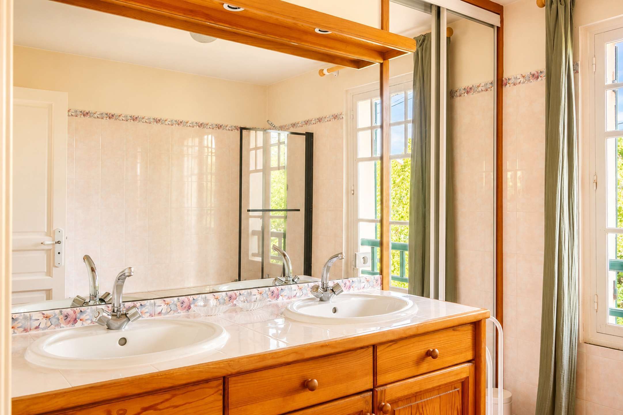 A bathroom with two sinks, a mirror, and a wooden vanity.
