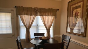 A dining area with a round table, four chairs, and a decorative bowl.