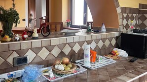 Una cocina con salpicadero de azulejos, un arco de madera, un televisor montado en la pared y varios utensilios de cocina sobre la encimera.