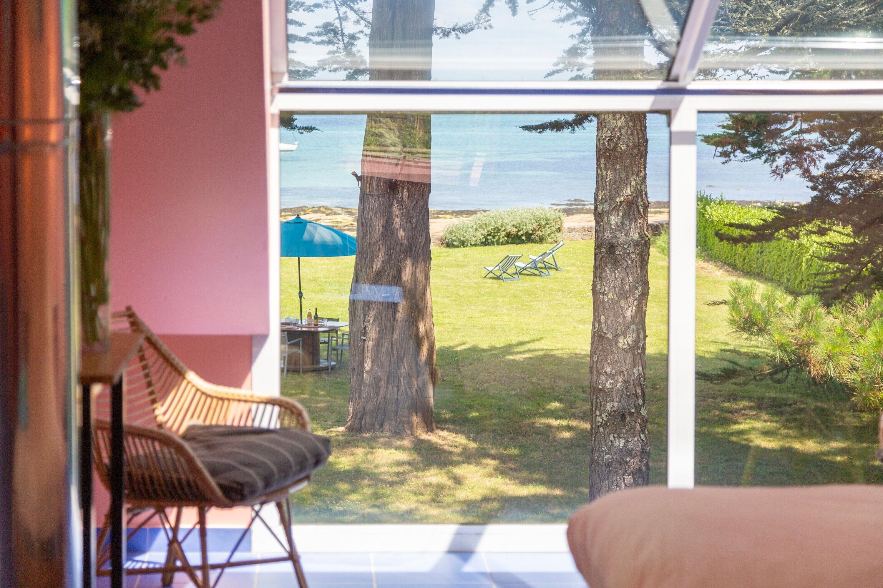 A room with a large glass window, wicker furniture, and a view of the outdoors.