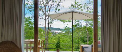 Ein Schlafzimmer mit einem großen Bett, einem Deckenventilator und Blick auf einen Balkon mit Gartenmöbeln und einem Blumentopf.