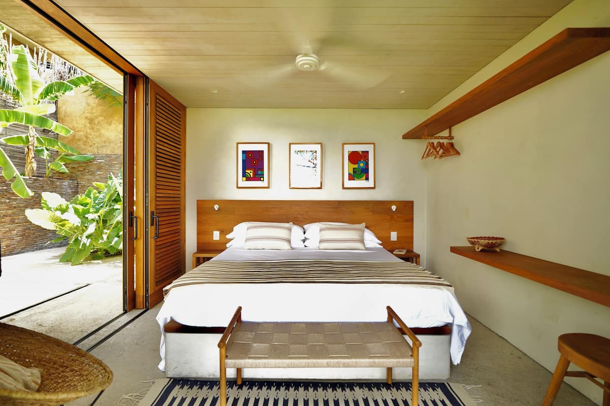 A bedroom with a large bed, wooden headboard, and three framed artworks on the wall.