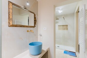 Ein Badezimmer mit einem blauen Waschbecken, einem spiegel mit goldener Rahmung und einer Duschkabine.
