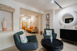 A modern living room with a sofa, armchairs, a round coffee table, and a black cabinet.