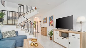 A modern living room with a staircase, a flat-screen TV, a coffee table with decorative items, and a sofa. - Holiday Home 'Casa Andalusia' with Sea View, Wi-Fi and Air Conditioning (Nerja)