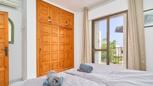 A bedroom with two beds, a large wooden wardrobe, and a balcony with a view. - Holiday Home 'Casa Andalusia' with Sea View, Wi-Fi and Air Conditioning (Nerja)