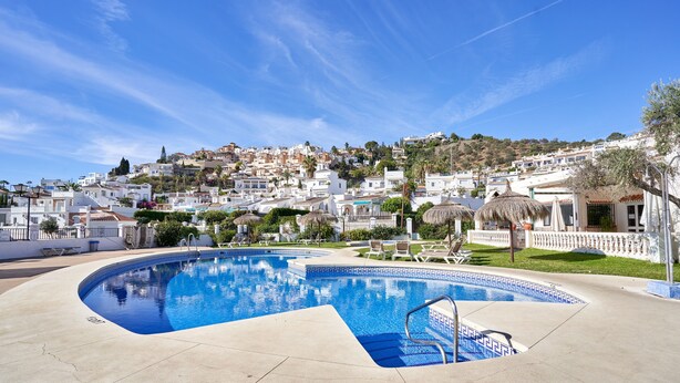 A swimming pool with a clear blue sky, white buildings, and a hilly landscape in the background. - Holiday Home 'Casa Andalusia' with Sea View, Wi-Fi and Air Conditioning (Nerja)