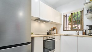 A modern kitchen with stainless steel appliances, white cabinetry, and a window with a view of greenery. - Holiday Home 'Casa Andalusia' with Sea View, Wi-Fi and Air Conditioning (Nerja)