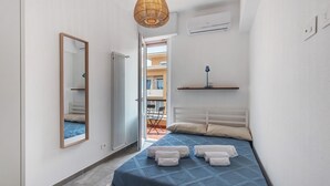 A bedroom with a bed, a mirror, a hanging light fixture, a shelf, and an air conditioning unit. - Queta – Modern Apartment: Comfort, Sea & City Center on Foot (Chiavari)