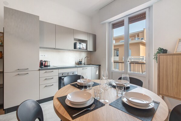 A modern kitchen with white cabinets, a microwave, and a dining area with a round table set for four.