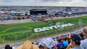 Un estadio con un gran letrero que dice 'DAYTONA' en el campo, rodeado de espectadores.