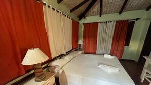 A bedroom with a large bed, a bedside table with a lamp, and curtains. - hotel palococo (Las Terrenas)