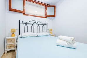 A bedroom with a bed, two bedside tables with lamps, a mirror, and a rolled towel on the bed. - Apartment 'Los Arcos' with Shared Pool, Wi-Fi and Air Conditioning (Alcocéber)