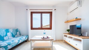 Une pièce moderne avec un canapé, une table sur laquelle se trouve une bouteille, un téléviseur et une étagère.