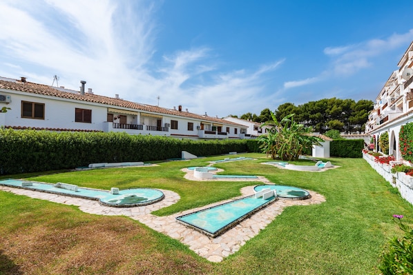 A courtyard with a swimming pool, white buildings, and green hedges. - Apartment 'Los Arcos' with Shared Pool, Wi-Fi and Air Conditioning (Alcocéber)
