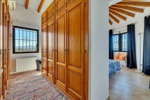 A room with a large wardrobe, a radiator, a window with a view, and a bed with a patterned bedspread. - Villa 'Amalia' with Sea View, Wi-Fi and Air Conditioning (Dénia)