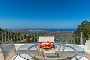 A glass table with a decorative bowl, a metal railing, and a view of the sea and cityscape. - Villa 'Amalia' with Sea View, Wi-Fi and Air Conditioning (Dénia)