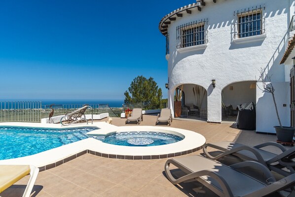 A pool area with a hot tub, lounge chairs, and a view of the ocean. - Villa 'Amalia' with Sea View, Wi-Fi and Air Conditioning (Dénia)