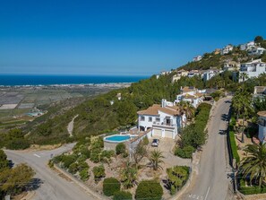 A hillside residential area with houses, a swimming pool, and a road. - Villa 'Amalia' with Sea View, Wi-Fi and Air Conditioning (Dénia)