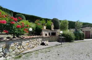 A stone wall with a garden, a small building with a chimney, and a clear sky.