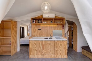 Una cocina compacta con armarios de madera, un lavamanos y una lámpara colgante.