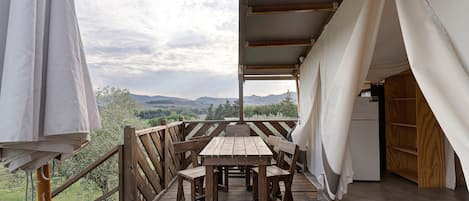 Una terraza de madera con una mesa y sillas, con vistas a un paisaje pintoresco.