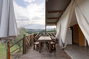 Una terraza de madera con una mesa y sillas, con vistas a un paisaje pintoresco.