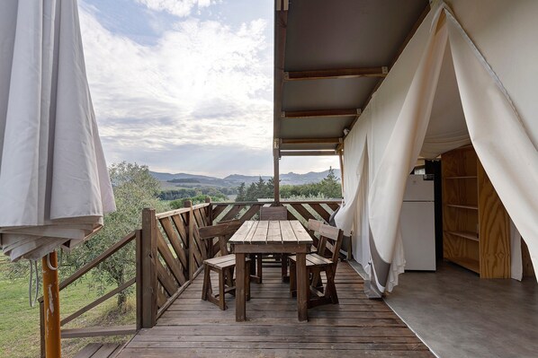 Eine Holzterrasse mit Tisch und Stühlen, mit Blick auf eine reizvolle Landschaft.