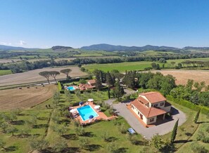 Una propiedad rural con piscina, una casa grande y amplios campos.