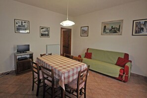 Un comedor con una mesa, sillas, televisor y sofá.