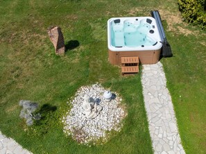 Un jacuzzi con un camino de piedra y un pequeño banco de madera.