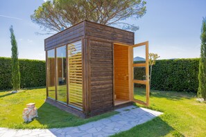 A wooden structure with large glass windows, a door, and a small step leading to it.