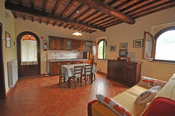 Una cucina rustica con mobili in legno, un tavolo da pranzo e un divano nella zona giorno.